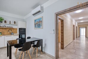 Eine moderne Küche mit Essbereich, einem Gemälde an der Wand und einem zur anderen Raum führenden Gang.