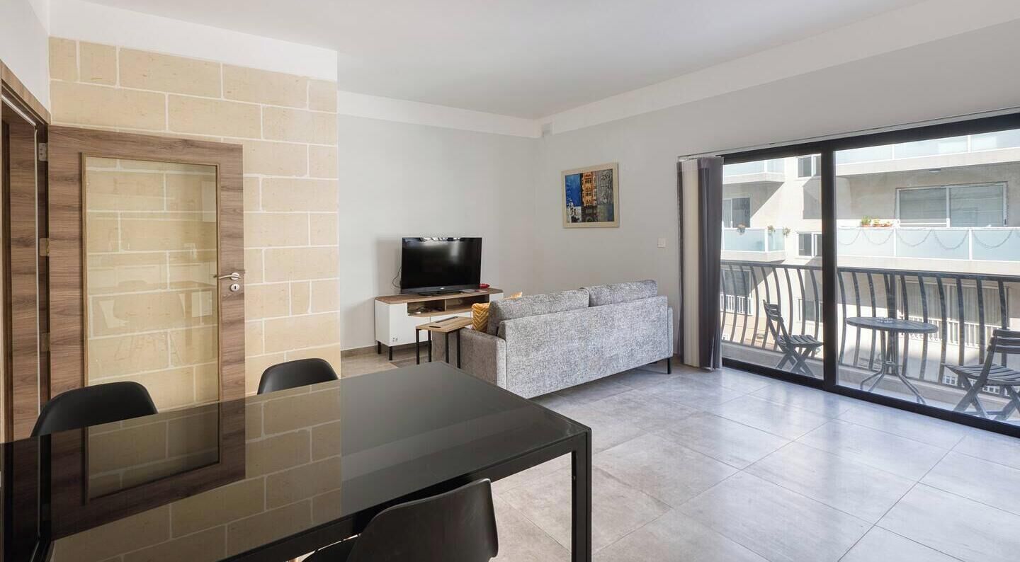 A modern living room with a dining table, sofa, and a TV.