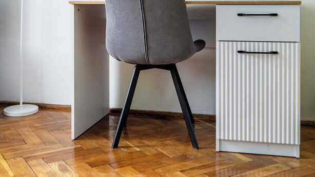 Et arbejdsområde med stol, skrivebord, lampe og radiator.