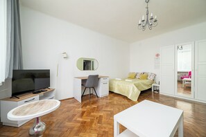 A modern bedroom with a TV, desk, chair, bed, and a dining table. - RentPlanet - Apartament Orla (Warszawa)