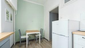Et lille køkken med et bord, stole, et køleskab og et vindue.