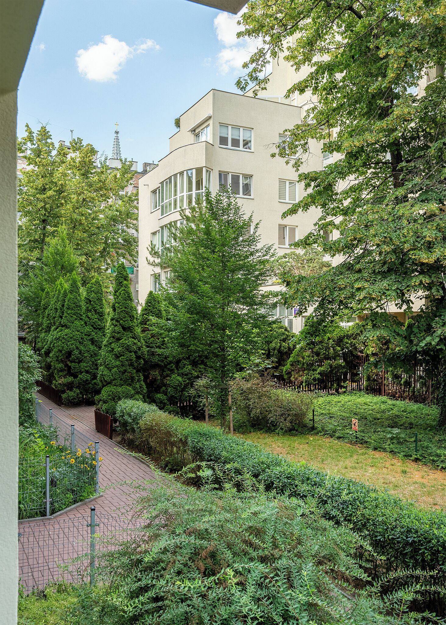 Un immeuble à plusieurs étages avec un jardin situé à l’avant.