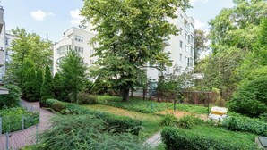 Et boligområde med et stort træ, en indhegnet have og en bygning med mange vinduer.