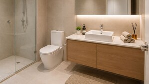 Ein modernes Badezimmer mit Glasdusche, Toilette, Waschbecken mit Spiegel und Holzwaschtisch.