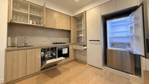 Eine moderne Küche mit Holzschränken, einem eingebauten Backofen, einem Geschirrspüler und einem Edelstahl-Kühlschrank.