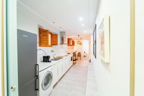 A modern kitchen with a washing machine, a coffee maker, and wooden cabinets. - Cozy Central Apartment in Burgos (Burgos)