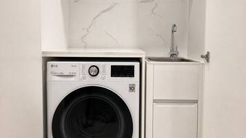 A compact laundry room with a washing machine, a small sink, and a cabinet.