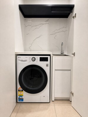 A compact laundry room with a washing machine, a small sink, and a cabinet. - Clayton 2BR1BA Apt Near Monash WIFI Parking (Clayton)