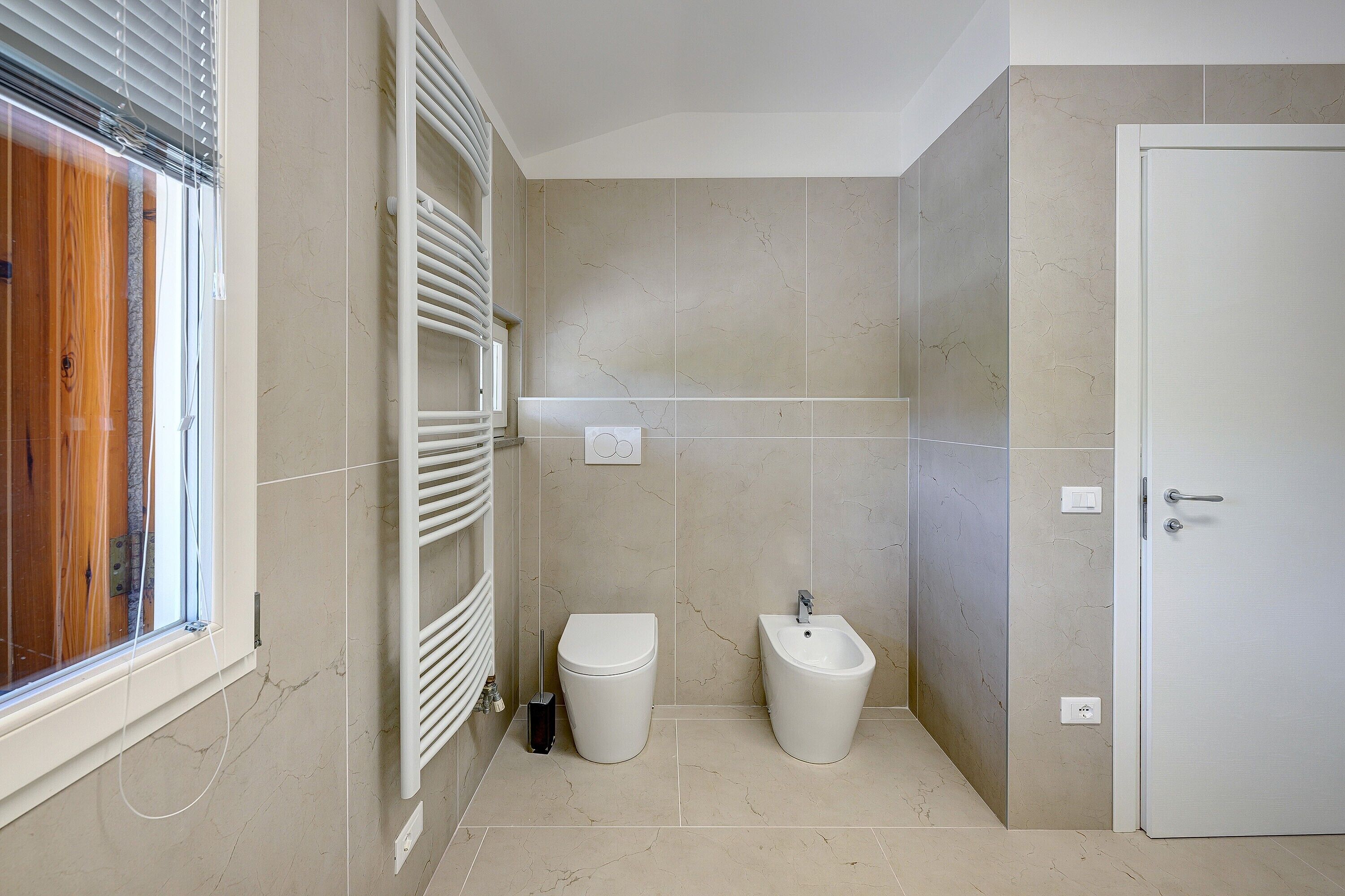 Une salle de bain comprenant des toilettes, un bidet et un espace douche.