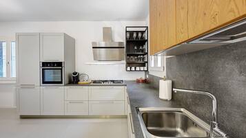 Una cucina moderna con mobili bianchi, un lavello in acciaio inossidabile e un forno integrato.