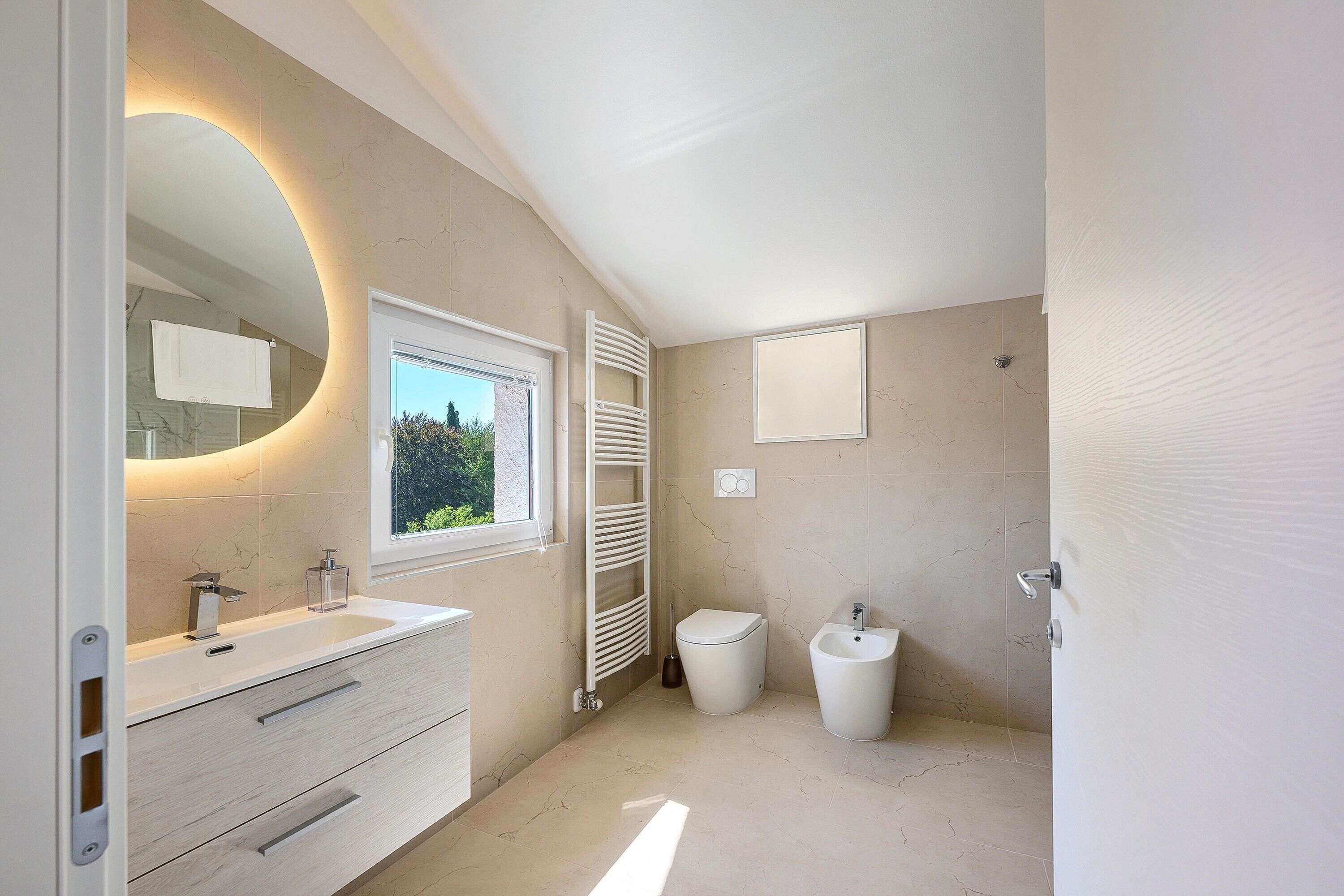 Un bagno moderno con un mobile lavabo, un bidet e una finestra.