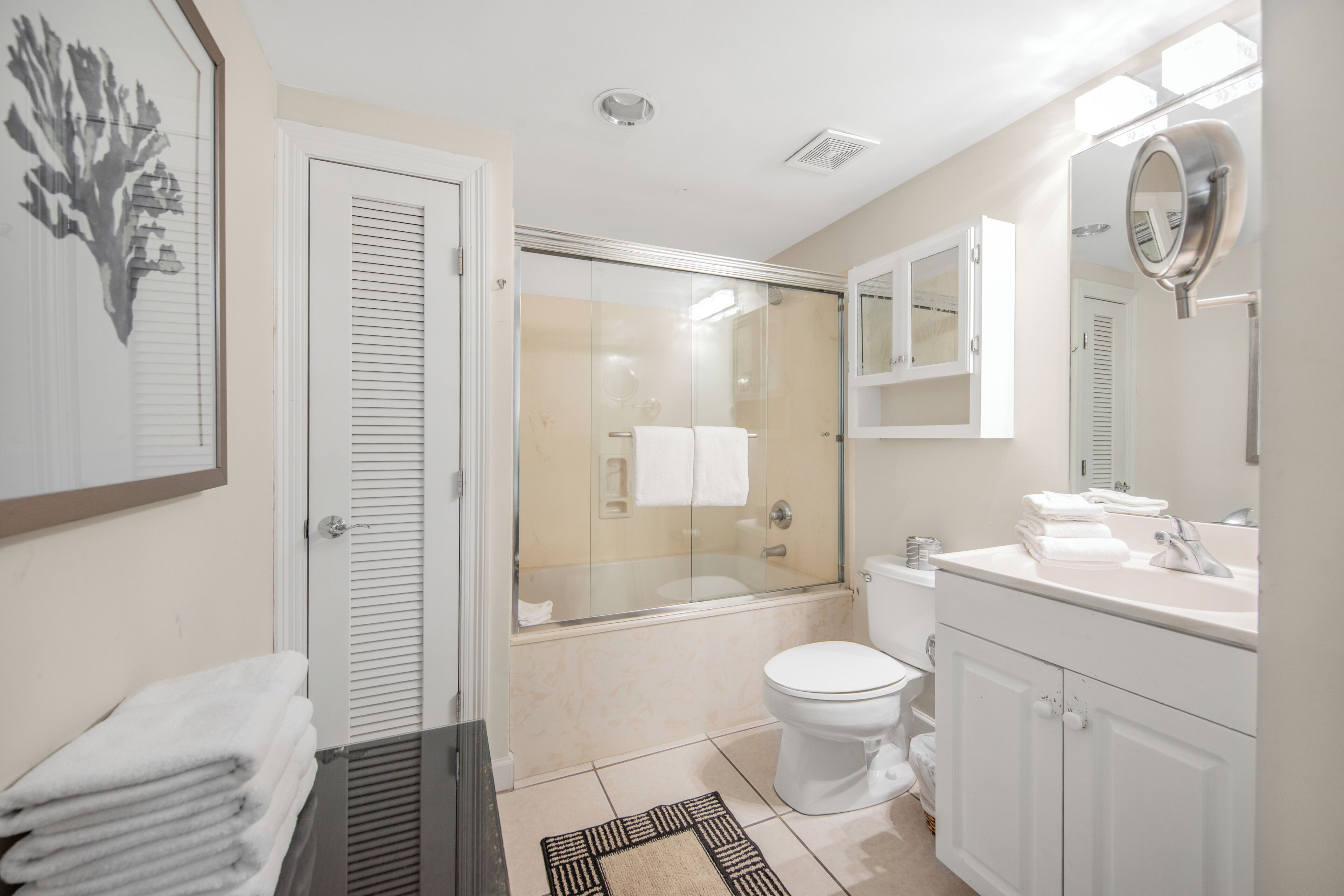 Une salle de bain avec une douche à parois de verre, des toilettes et un lavabo avec un miroir au-dessus.