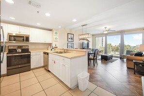 A modern kitchen with stainless steel appliances, a dining area with a view, and a balcony with a view. - Beach Resort Getaway | Private Beach Access | Sleeps 6 | Resort Pools (Destin)