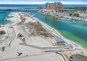 An aerial view of a coastal area with a marina, a large hotel, and a beach with construction. - Beach Resort Getaway | Private Beach Access | Sleeps 6 | Resort Pools (Destin)