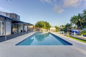 A swimming pool with a clear blue water surface, surrounded by a concrete deck.