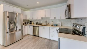 A modern kitchen with stainless steel appliances, white cabinetry, and a tiled backsplash. - 3 Mi to Hollywood Beach! Canal-front Haven w/ Dock (Hollywood)