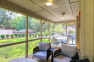 A covered patio with wicker furniture, a table, and a view of the backyard.