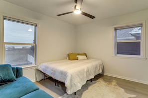 Ein Schlafzimmer mit einem Bett, einem Deckenventilator, einem Fenster und einem Sofa.
