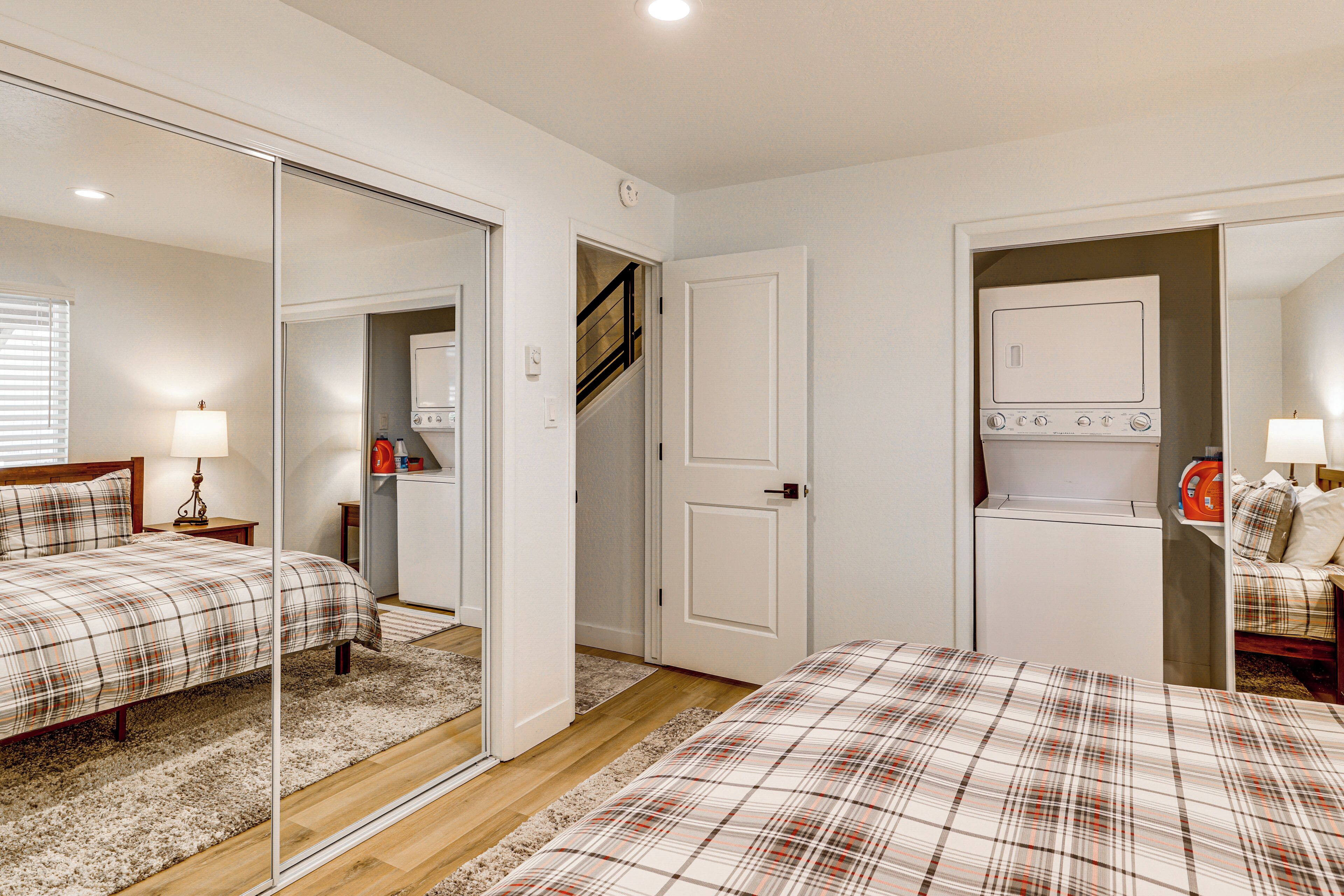 A bedroom with a bed, a mirror, a wardrobe, and a built-in washing machine.