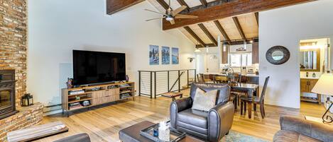 A spacious living room with a fireplace, leather sofas, a television, and a dining area with wooden furniture.