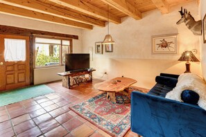 Ein Wohnzimmer mit Holzboden, einer Couch, einem Fernseher, einem Tisch und einem Teppich.