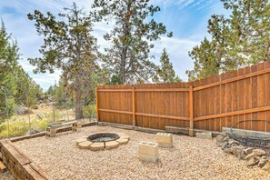 An outdoor patio with a fire pit, seating, and a wooden fence. - Fire Pit & Wildlife Views! Tranquil Bend Retreat (Bend)