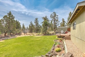 A house with a well-maintained lawn, a deck with outdoor furniture, and a wooden fence. - Fire Pit & Wildlife Views! Tranquil Bend Retreat (Bend)
