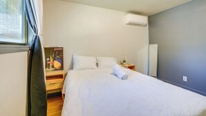 A neatly made bed with white linens, a bedside lamp, and a poster on the wall.