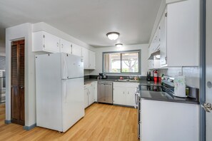 A kitchen with white cabinets, a dishwasher, a refrigerator, and a window providing natural light. - 3 Mi Dtwn! Eugene Family Retreat w/ Yard & Patio (Eugene)
