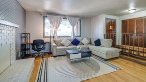 A modern living room with a sofa, a coffee table, a desk with a chair, and a wardrobe.