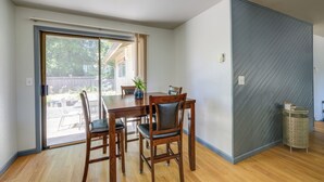 A dining area with a table, chairs, and a view through a sliding glass door.