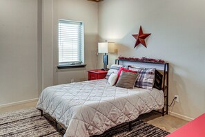 A bedroom with a bed, a nightstand, a lamp, a window, and a wall decoration. - 9 Mi to Dtwn: Barndominium in Lubbock (Lubbock)