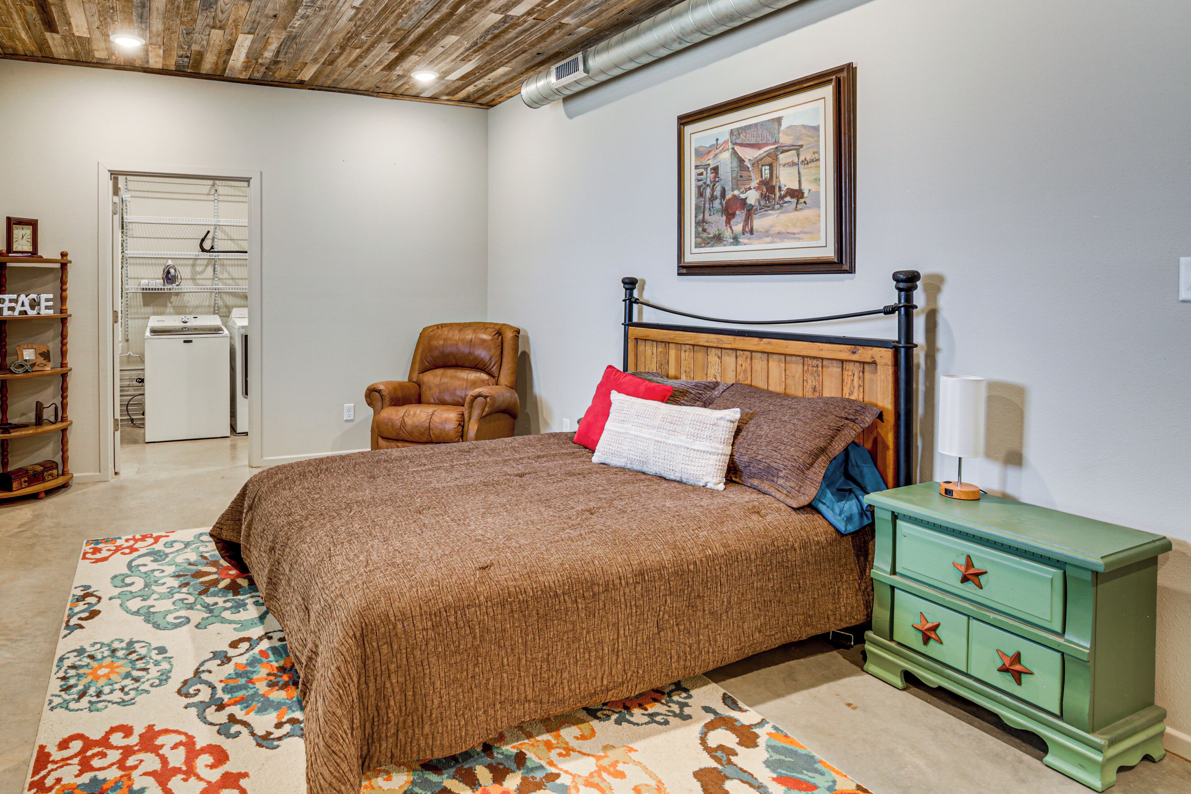 A bedroom with a bed, a chair, a nightstand, a dresser, and a painting on the wall.