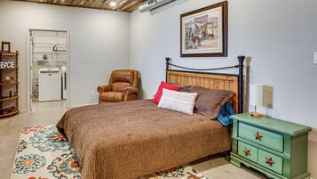 A bedroom with a bed, a chair, a nightstand, a dresser, and a painting on the wall.