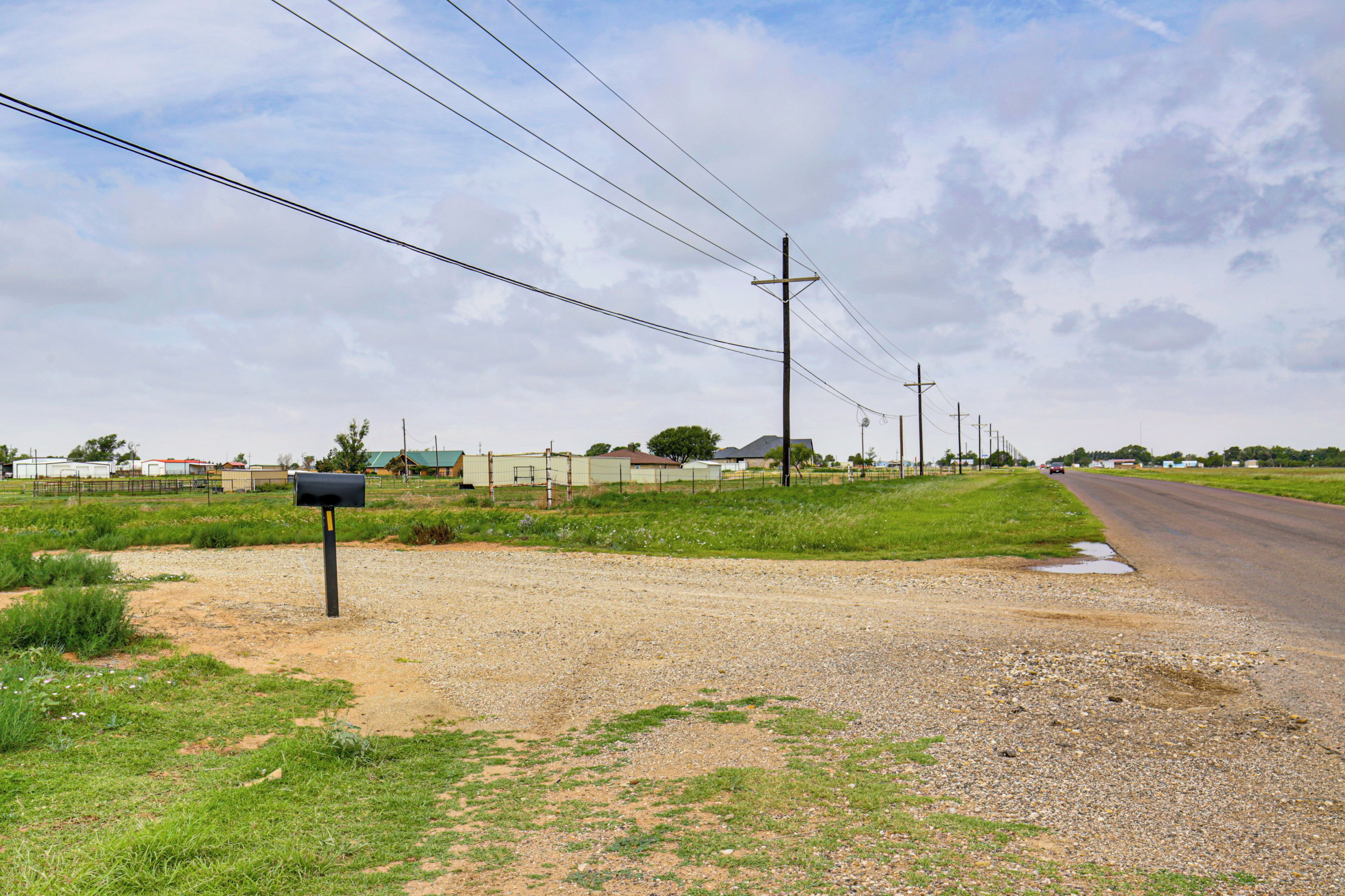 Uma estrada rural com uma caixa de correio, postes de eletricidade e um caminho de cascalho.