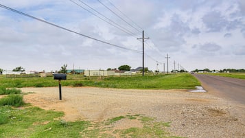 Uma estrada rural com uma caixa de correio, postes de eletricidade e um caminho de cascalho.
