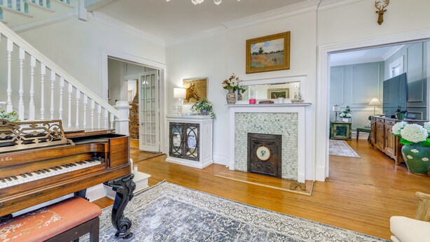 A grand piano, a fireplace, a chandelier, and a staircase. - 4BR Historic Home Located in Downtown New Bern (New Bern)