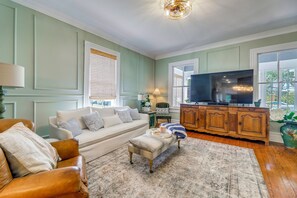 Ein Wohnzimmer mit Sofa, Hocker, Holzschrank und Fernseher.