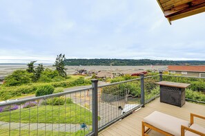 Eine Terrasse mit Bank und Tisch, mit Blick auf ein Wohngebiet mit Häusern und einem Gewässer.