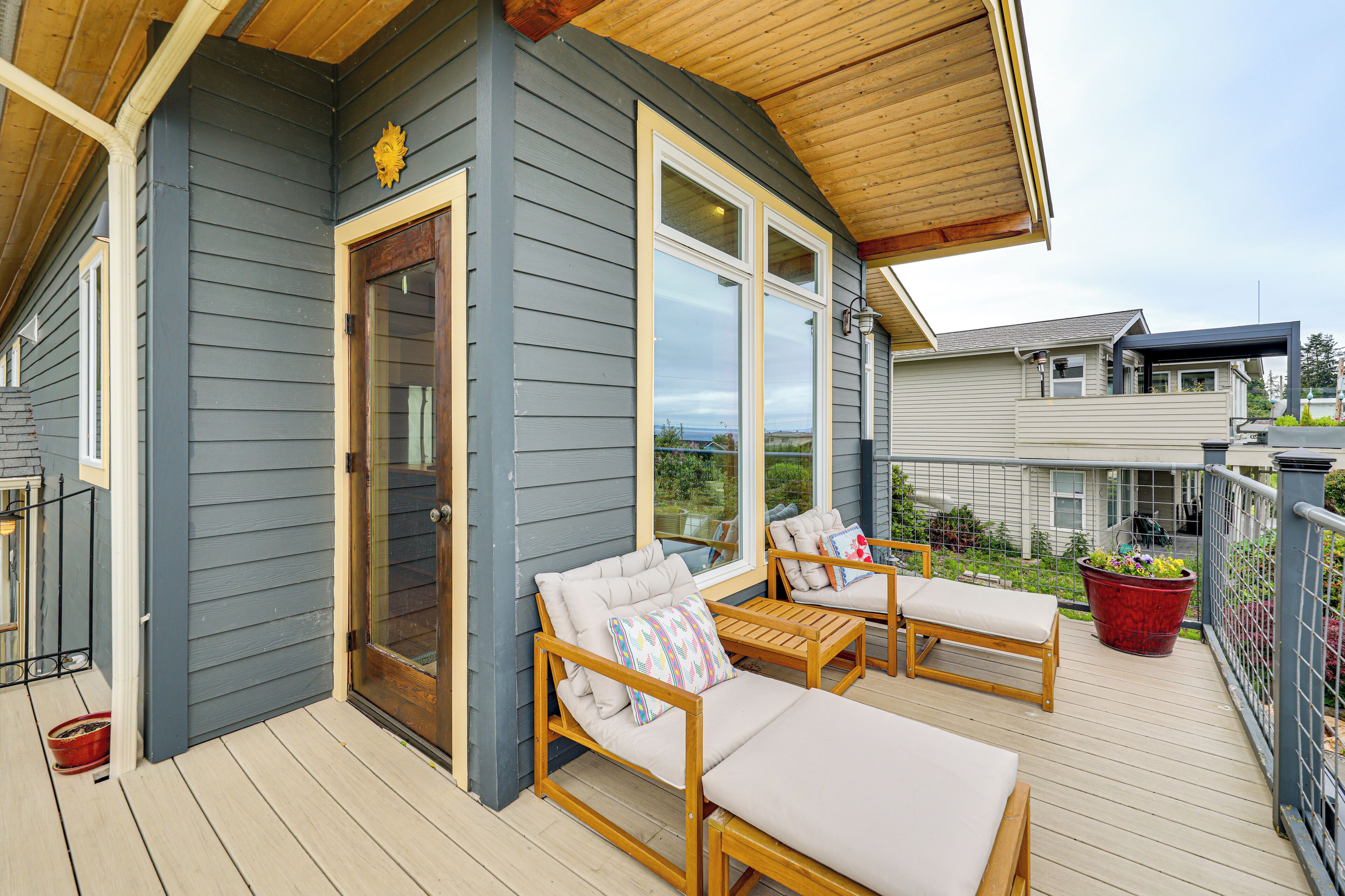 A wooden deck with two lounge chairs and a red planter.