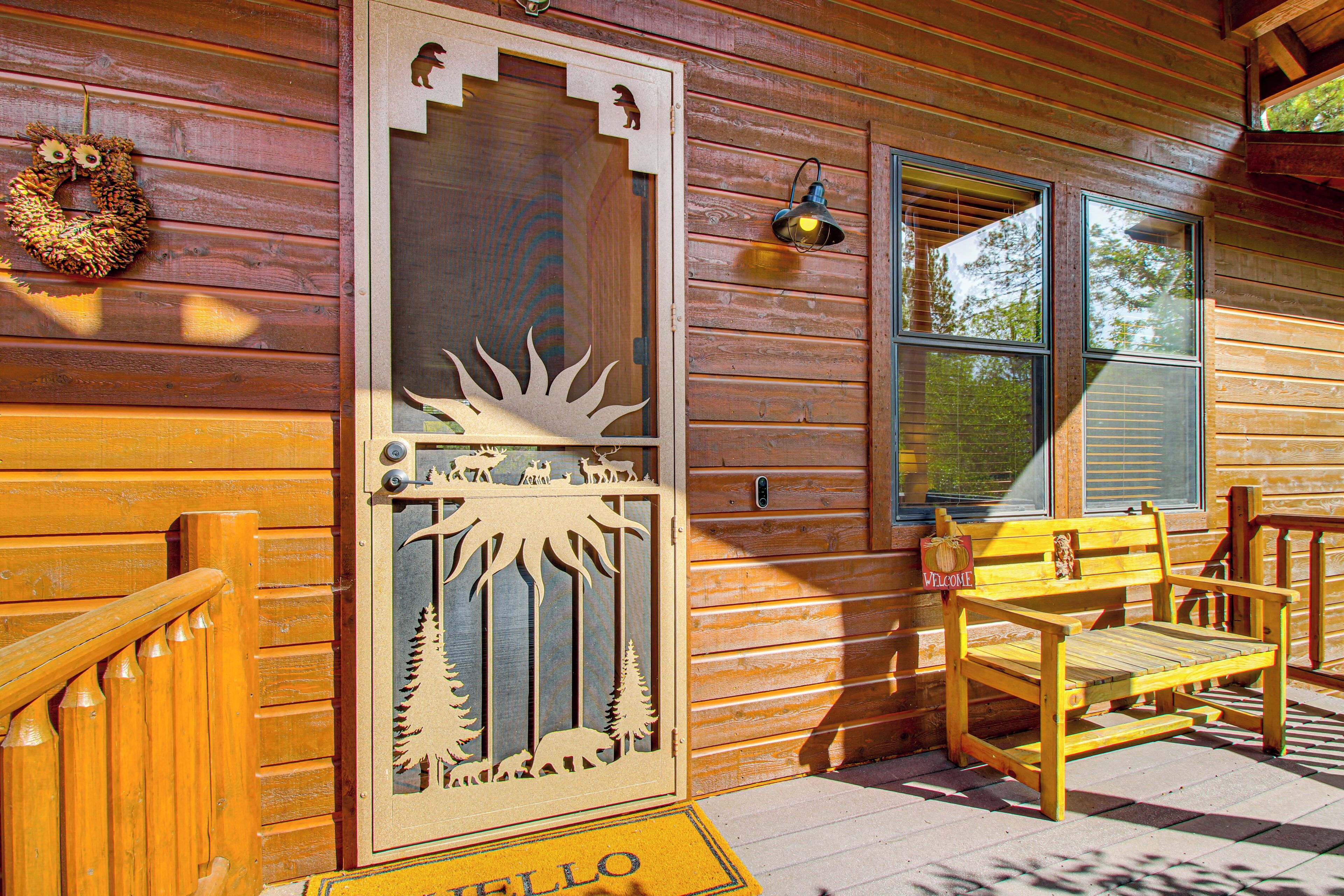 A wooden cabin with a decorative door, a bench, and a welcome mat.