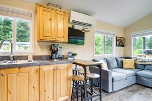 A modern kitchen with wooden cabinets, a built-in stove, and a bar area with stools. - Walk to Sol Duc River! Cozy Home Near Forks (Beaver)