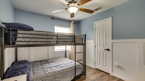 A bunk bed room with a ceiling fan, a door, and a window. - 4 Mi to Dtwn: Garland Getaway w/ Fenced-in Yard (Garland)