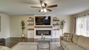 A living room with a ceiling fan, a fireplace, a television, and a sofa.