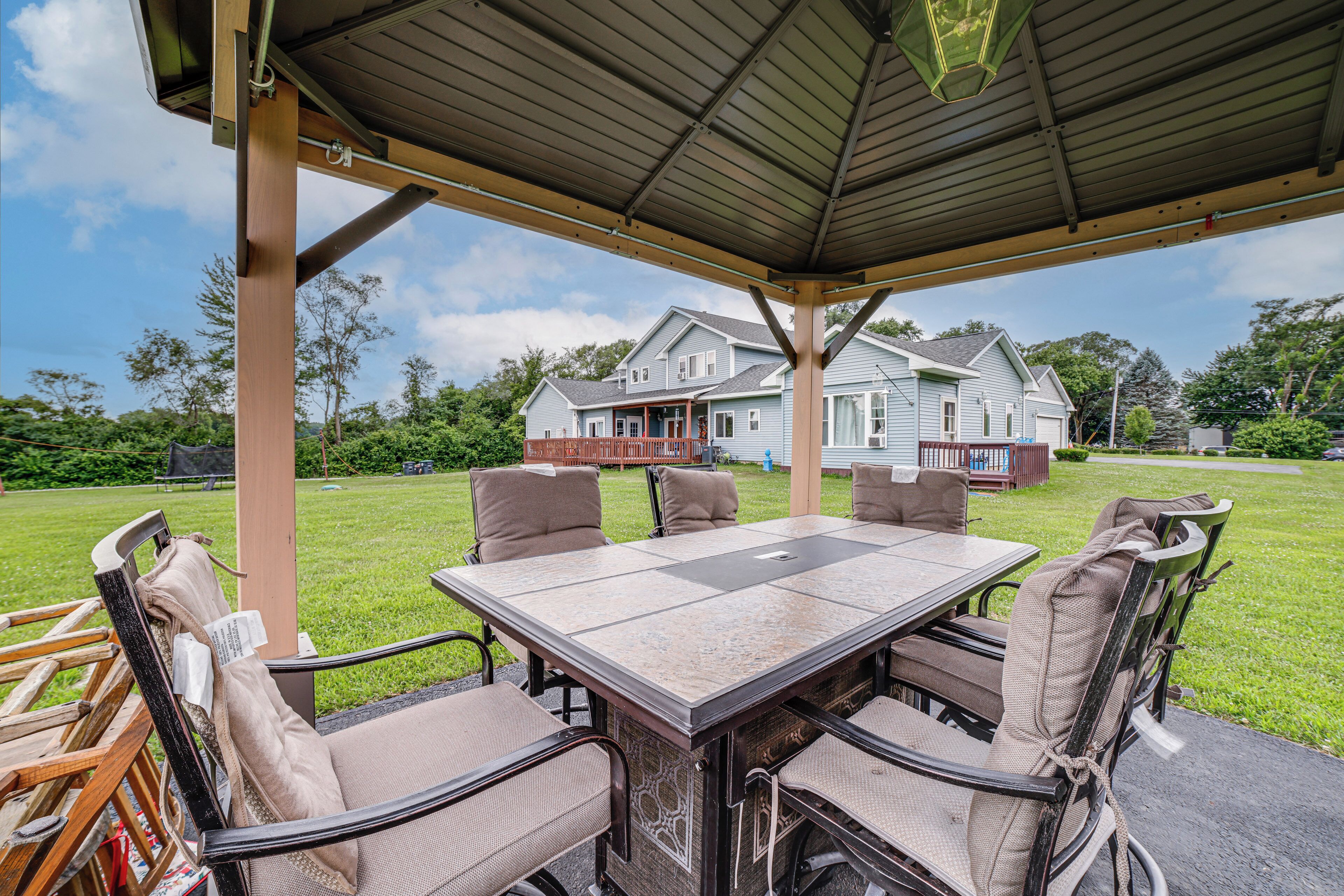 Une terrasse extérieure avec une table et des chaises, un espace abrité et une maison en arrière-plan.