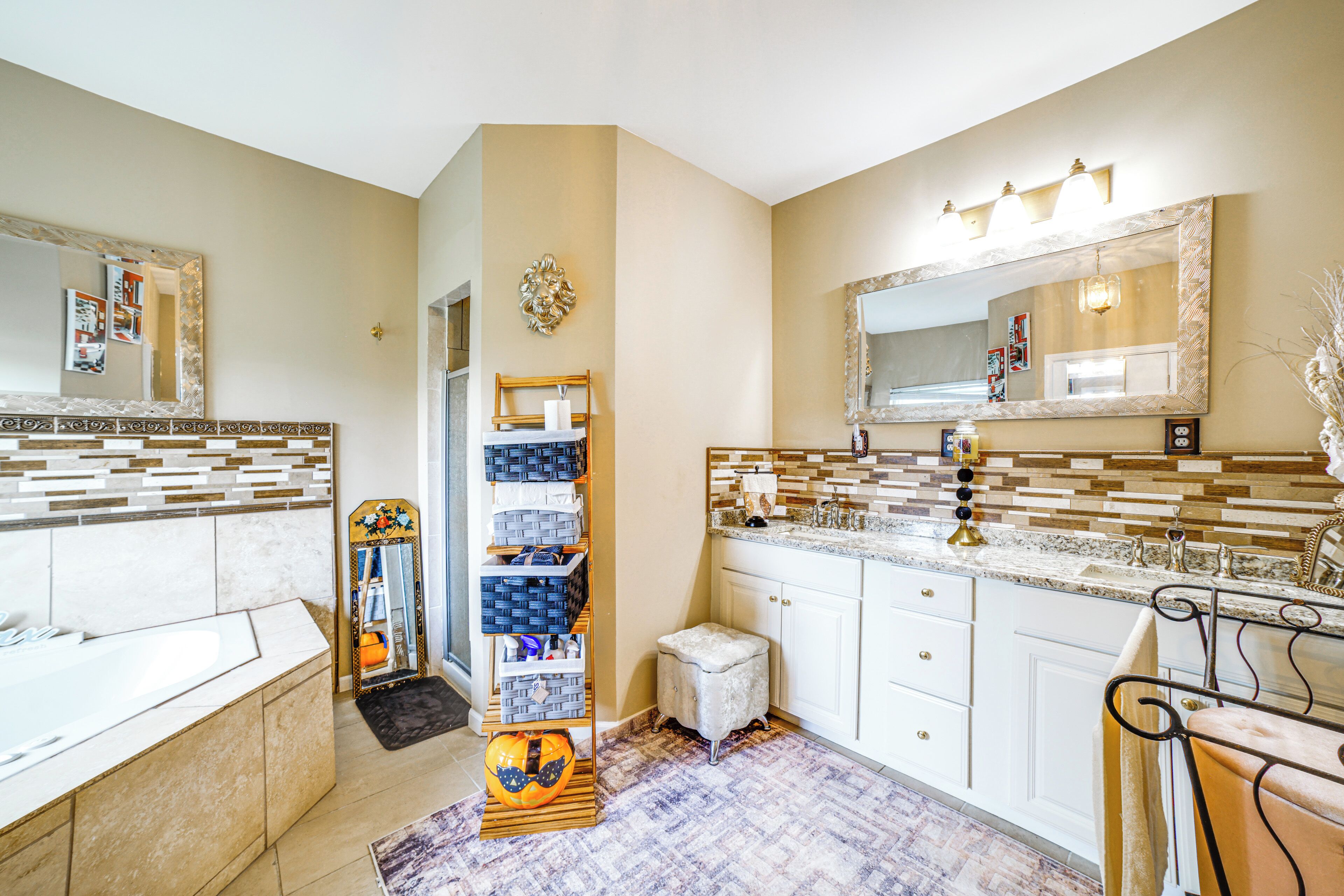 Une salle de bain avec une baignoire, un meuble-lavabo, un miroir, des étagères contenant des articles de toilette et une citrouille décorative.