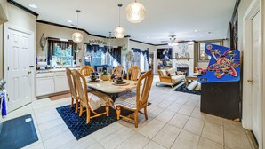 A spacious kitchen with a dining area, wooden chairs, and pendant lighting.