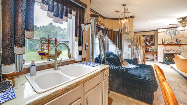 A kitchen with a double sink, a view of the outdoors, and a staircase leading to another level.