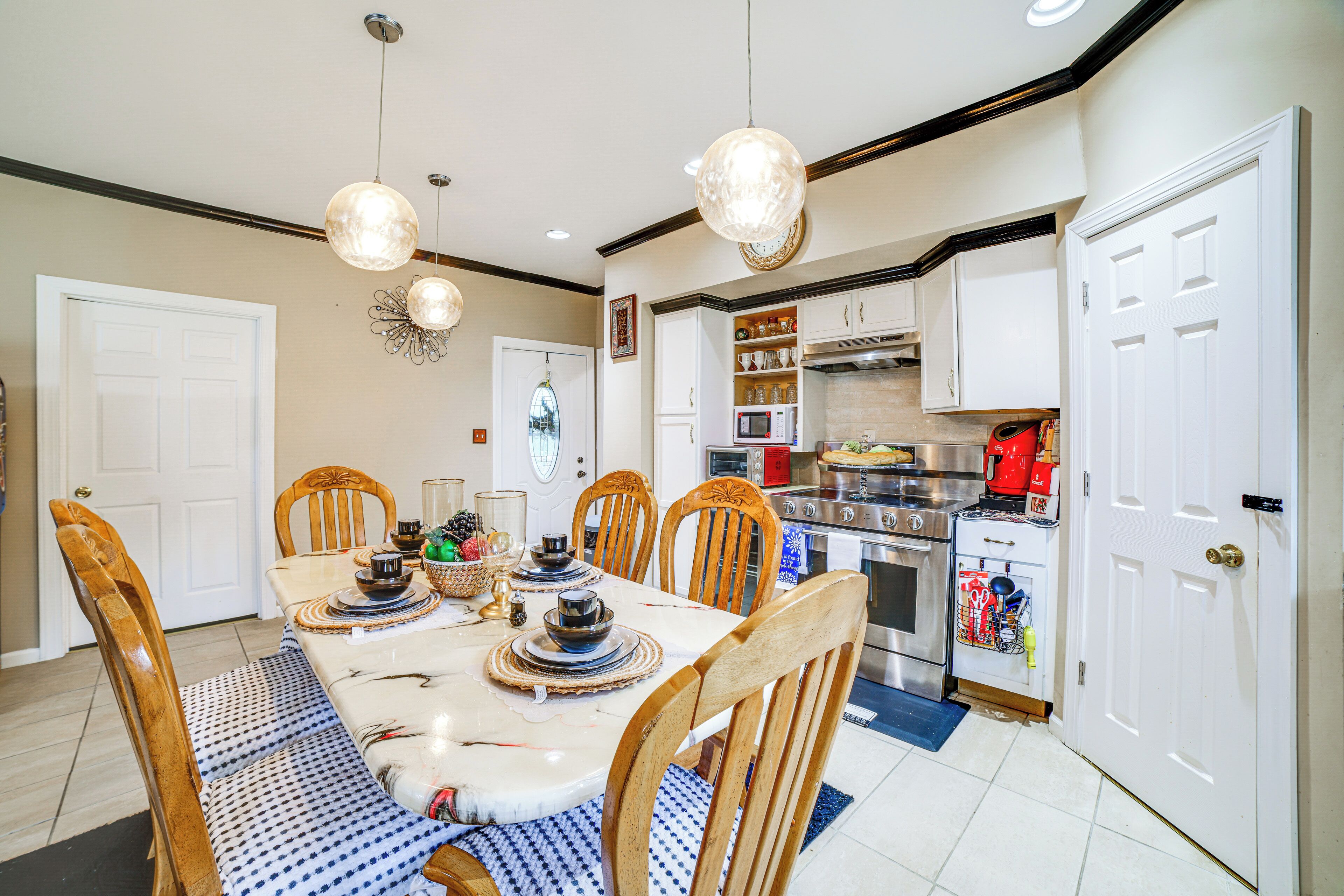 A dining area with a table set for four, surrounded by chairs, and a kitchen area with appliances and cabinets.