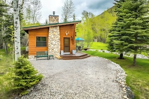 Eine Holzhütte mit Natursteinfassade und einem Kiesweg.